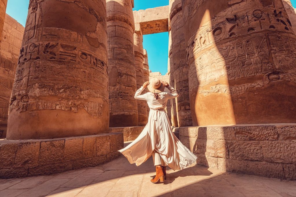 Женщина среди ряда колонн с вырезанными иероглифами, которые египтяне использовали вместо букв в Алфавите.
